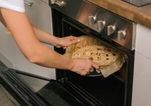 A baker placing a pie into the oven