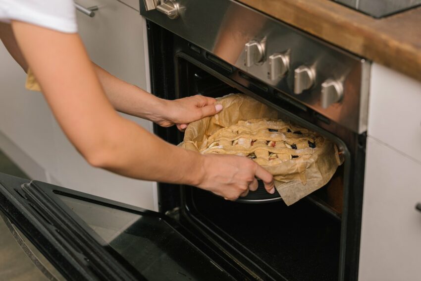 A baker placing a pie into the oven